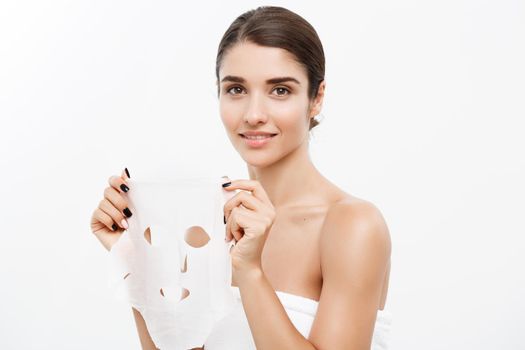 Beauty Skin Care Concept - Beautiful Caucasian Woman applying paper sheet mask on her face white background