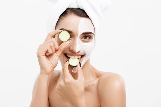 Beauty Youth Skin Care Concept - Portrait Beautiful Caucasian Woman apply cream and holding fresh cucumber in front of her face.Isolated over white background