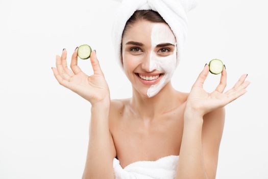 Beauty Youth Skin Care Concept - Portrait Beautiful Caucasian Woman apply cream and holding fresh cucumber in front of her face.Isolated over white background