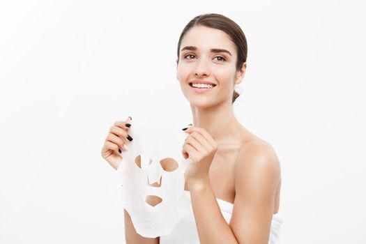 Beauty Skin Care Concept - Beautiful Caucasian Woman applying paper sheet mask on her face white background