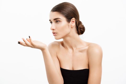 Health care and spa concept - attractive young and healthy woman blowing a kiss from her hand white background