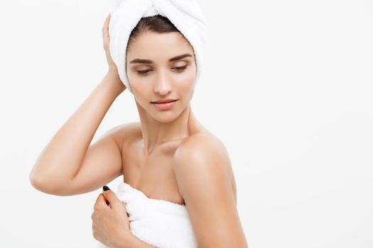 Beauty and Skin care concept - Beautiful caucasian Young Woman with bath towel on head covering her breasts, on white