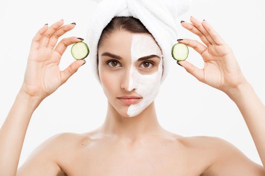 Beauty Youth Skin Care Concept - Portrait Beautiful Caucasian Woman apply cream and holding fresh cucumber in front of her face.Isolated over white background