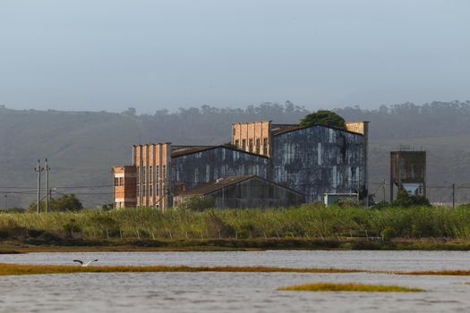 Abandoned and dilapidated old factory building on estuary riverbank, Mossel Bay, South Africa