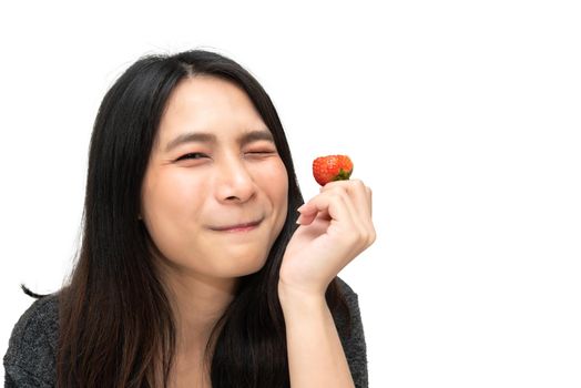 Asian pretty woman holding and eating fresh strawberry is red berry fruit color and sweet juicy with enjoy and happy emotion in concept food, healthy eating in life