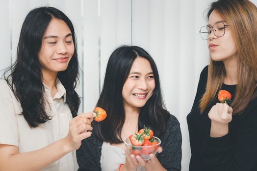 Asian pretty women holding and eating fresh strawberry is red berry fruit color and sweet juicy with enjoy and happy emotion in concept food, healthy eating in life