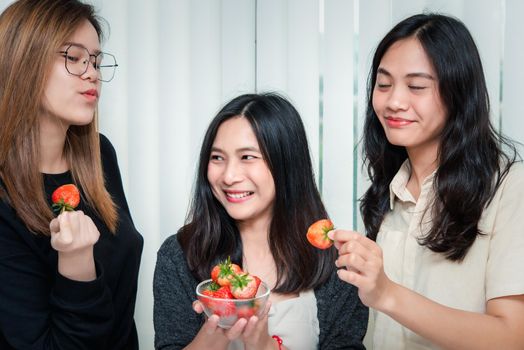 Asian pretty women holding and eating fresh strawberry is red berry fruit color and sweet juicy with enjoy and happy emotion in concept food, healthy eating in life