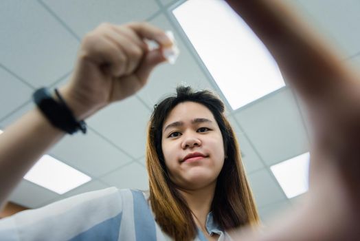 Asian woman use eye drop or artificial tears by drops in to the eye for someone else (POV) for inflammation or dryness problem therapy of eyeball for eyes health