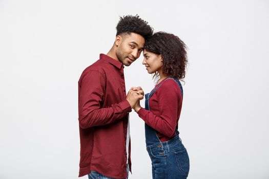 Side view of beautiful African American young couple in classic shirts holding hands, looking at each other and smiling