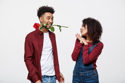 Romantic African American man in Love, holding a rose between his teeth standing in front of his girlfriend