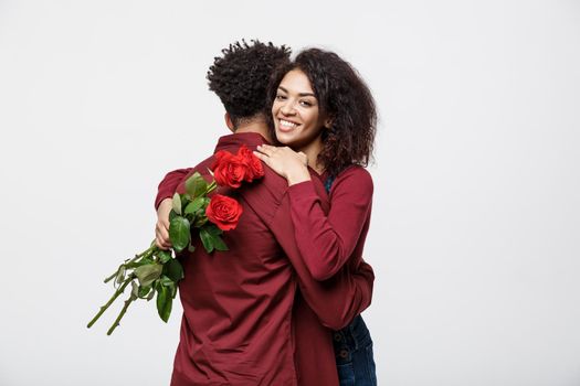 Couple Concept - Young african american couple huging each other and holding romantic red rose