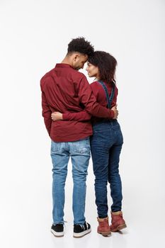 Full lenght back view of young African American couple hugging together isolated on white background.