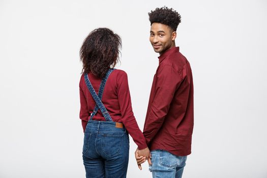 Portrait rear view of young afro american couple holding hands isolated on white background.