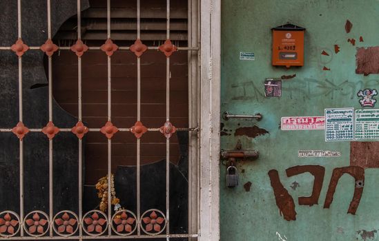 Bangkok, Thailand - 25 Jan 2020 : Detail of an old house with blue wooden door and steel window frame. Facade of an old traditional house. Selective focus.