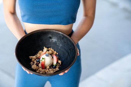 Woman served ice cream bowl with fruit and granola.