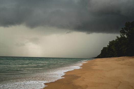 Tropical beach with white sand and dark storm clouds.