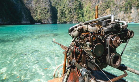 Old Machine of Fishing boat at the clear blue sea water in Thailand.