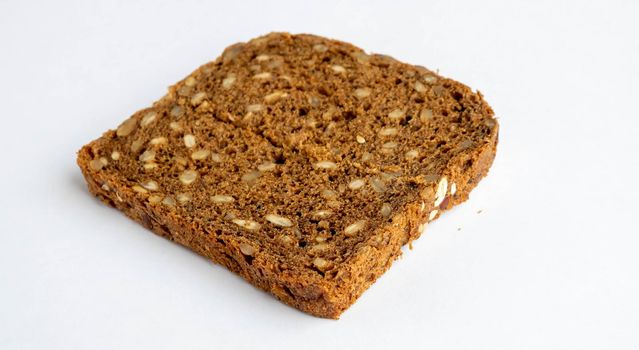Slice of whole-grain dark bread, isolated on a white background close-up.