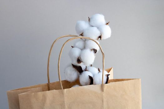 Organic eco-friendly paper bag with cotton flowers on a gray background. Zero waste and eco-friendly concept.