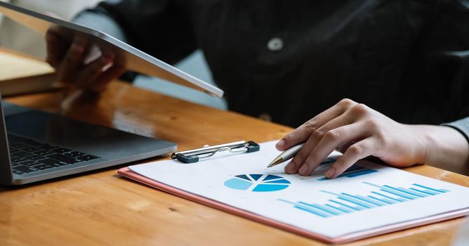 Business woman using tablet computer for analysis financial report.