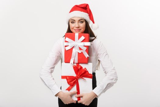 Business Concept - Beautiful young caucasian business woman with santa hat holding a lot of gift boxes with copy space on side.