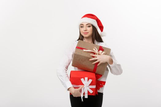 Business Concept - Beautiful young caucasian business woman with santa hat holding a lot of christmas gift boxes with copy space on side.