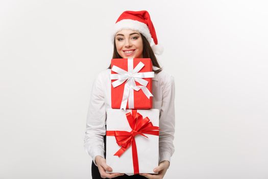 Business Concept - Beautiful young caucasian business woman with santa hat holding a lot of christmas gift boxes with copy space on side.