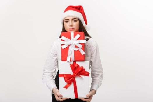 Business Concept - Beautiful young caucasian business woman with santa hat holding a lot of gift boxes with worry facial expression.