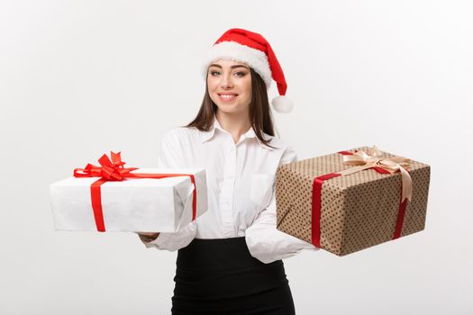 Christmas Concept - young happy caucasian business woman with santa hat giving a choice of gift boxs to camera with copy space on side.