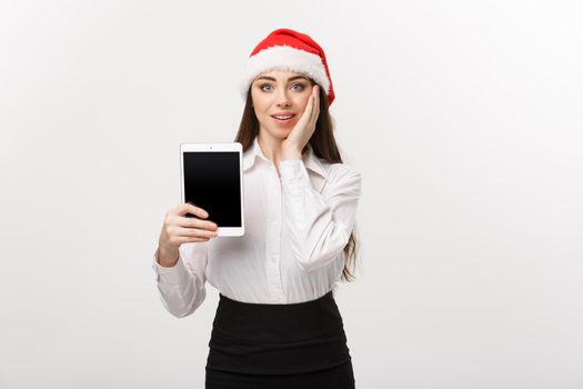 Business Concept - young caucasian business woman in Christmas theme showing digital tablet with surprising facial expression.