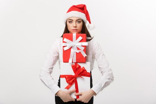 Business Concept - Beautiful young caucasian business woman with santa hat holding a lot of gift boxes with worry facial expression.