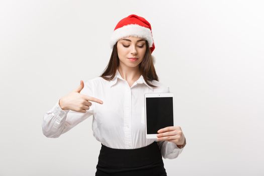 Business Concept - young caucasian business woman in Christmas theme showing and pointing to digital tablet.