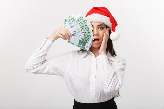 Christmas and finance concept - Young business woman showing money closing her face with surprise expression.