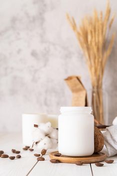 Home decoration and interior. Beautiful burning candles with cotton flowers and coffee beans on white wooden background