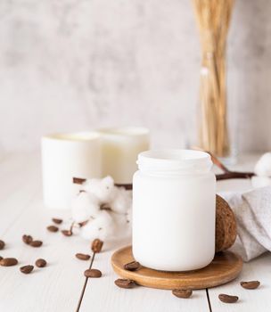 Home decoration and interior. Beautiful burning candles with cotton flowers and coffee beans on white wooden background