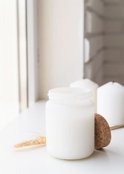 Mock up design. Home decoration and interior. Beautiful white candle with wheat spikes on white background