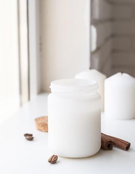 Mock up design. Home decoration and interior. Beautiful white candle with cinnamon sticks and coffee beans on white background