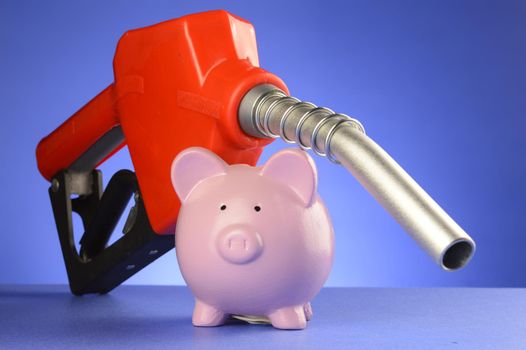 A concept of saving money at the gas pumps using a piggy bank and red fuel pump over a blue background.