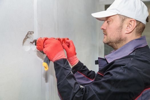 The electrician inserts the plastic box directly into the outlet holes. Close-up