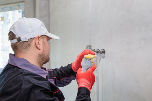 An electrician drills holes for sockets with a diamond core bit. Close-up