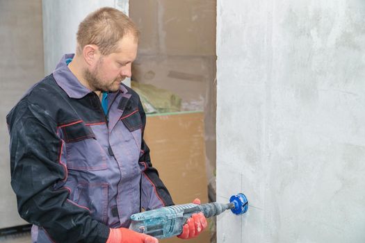 An electrician drills holes for sockets with a diamond core bit. Close-up