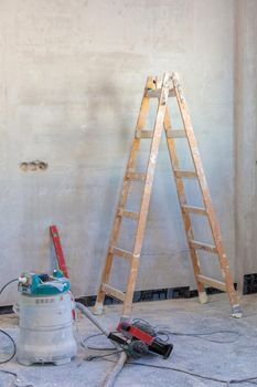 A room with a stepladder and a tool for repairs in the process of finishing the apartment.