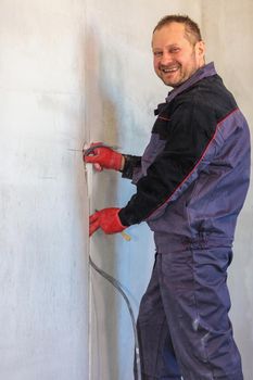 An electrician is laying a cable in an electrical ditch. Apartment renovation. Close-up