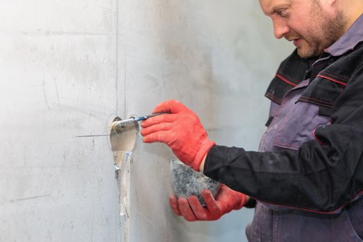The electrician will prime the holes and channels for outlets and wires. Repair of apartments. Close-up