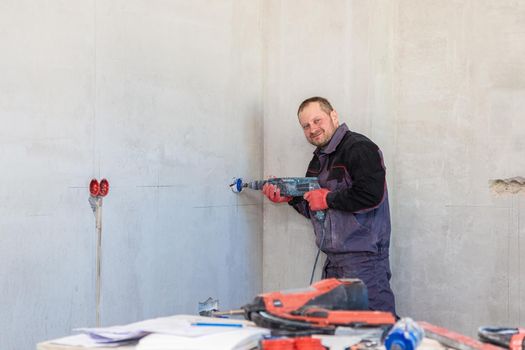 An electrician drills holes for sockets with a diamond core bit. Close-up