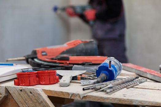 An electrician drills holes for sockets with a diamond core bit. Close-up