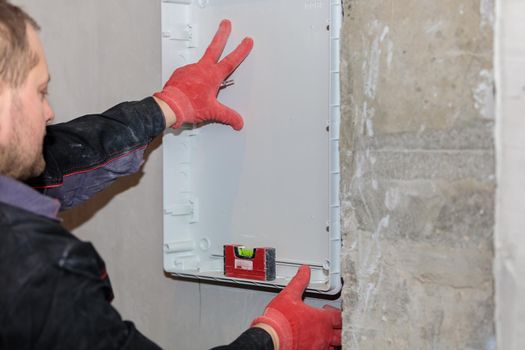 The electrician tries on and marks the lines of the electrical panel. Repair of apartments. Close-up