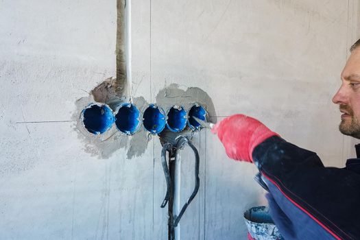 The electrician will plaster holes and channels for sockets and wires. Repair of apartments. Close-up