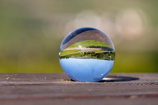 Crystal ball on wooden table shows landscape of river Moselle