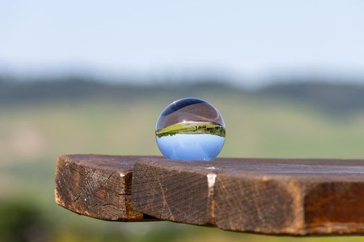 Crystal ball on wooden table shows landscape of river Moselle